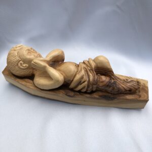 Wooden sculpture of a reclining child with detailed carving.
