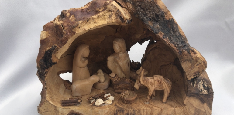 Wooden nativity scene carved in tree trunk.