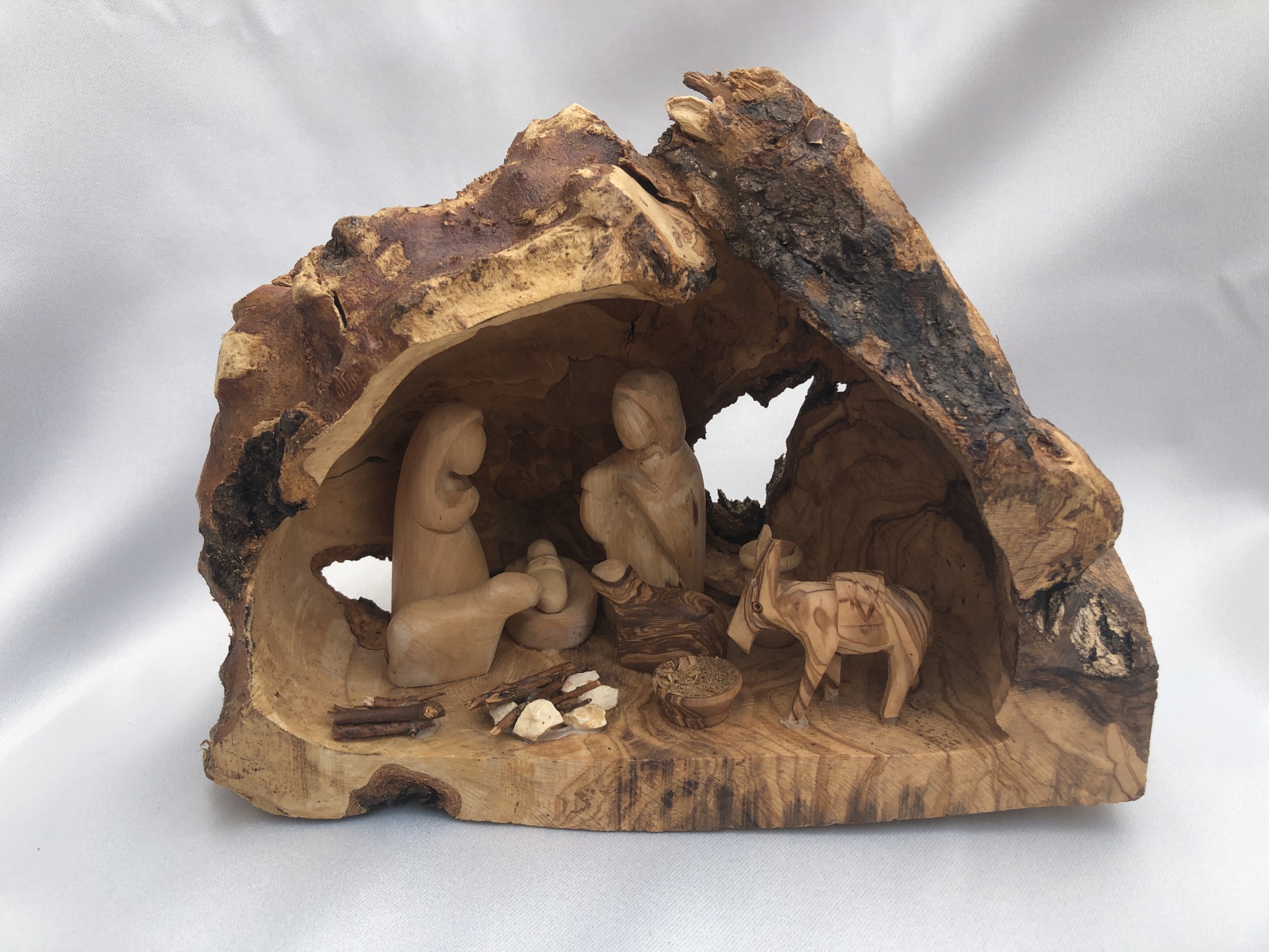 Wooden nativity scene carved in tree trunk.